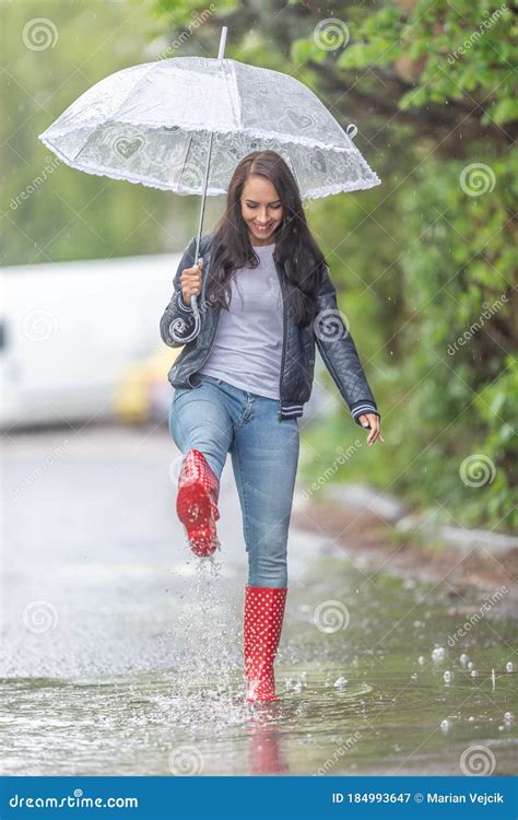 woman with an umbrella walking in rainboots in a puddle under a heavy rain stock image image