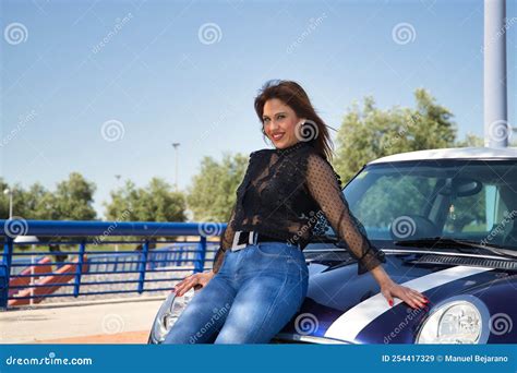 Attractive Mature Woman In Black Transparent Shirt And Jeans Smiling