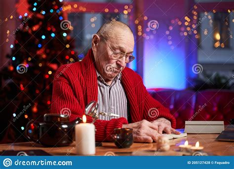 Bald Old Man With Glasses Sitting At Table And Writing Xmas Cards Stock