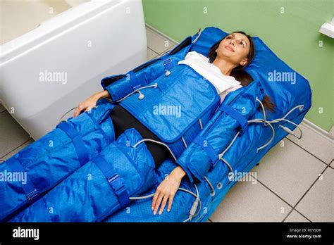 Woman In Pressotherapy Suit Lying Down Having Pressure Therapy For Weight Loss In Spa Salon