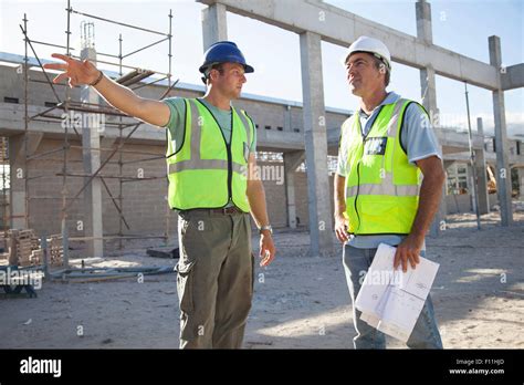 Caucasian Construction Workers Talking At Construction Site Stock Photo
