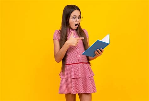 Школьница подросток с книгами на изолированном студийном фоне шокированная удивленная девочка