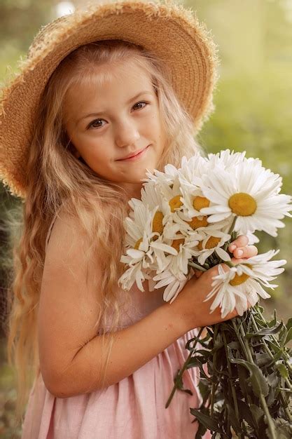 Premium Photo A Beautiful Blonde Girl In A Straw Hat With White Daisies In Her Hands