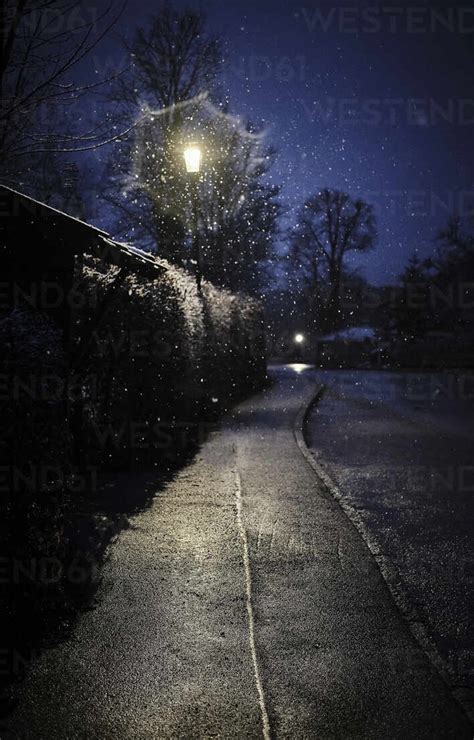 Street Light Illuminating Empty Sidewalk At Winter Night Stock Photo