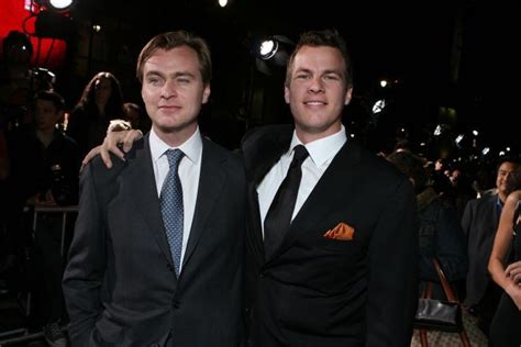 Two Men In Suits Standing Next To Each Other On A Red Carpet At An Event