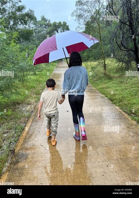 Brother And Sister Walk In The Rain Under An Umbrella Stock Photo Alamy