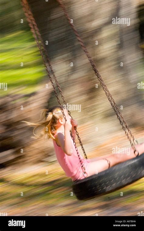 Young Girl Swinging On A Tire Swing On A Summer Day In Florida Stock