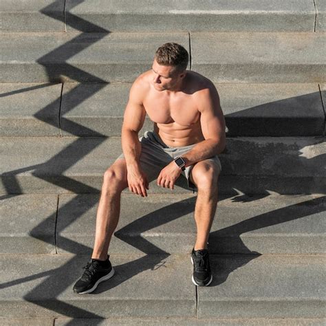 Free Photo Front View Shirtless Athletic Man Sitting On Stairs