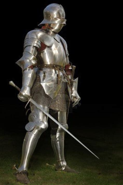 medieval knight in shining armour of the 15th century standing outside with sword isolated on a