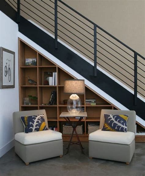 Two Chairs Sitting In Front Of A Book Shelf Under A Stair Case Next To
