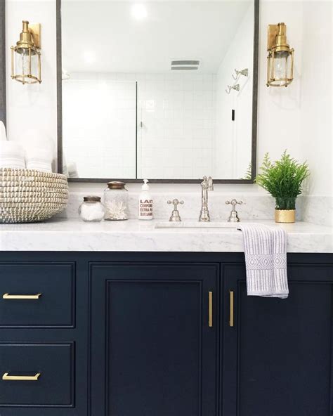 Get a fresh perspective for this online. Bathroom with navy cabinets, marble countertops, and gold ...