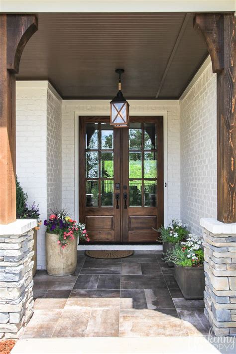 A Front Door With Two Planters On Each Side And A Lantern Hanging From