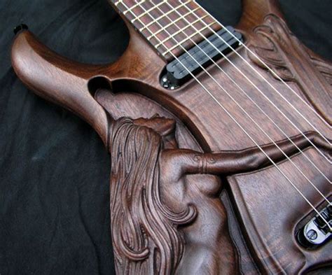 An Intricately Carved Wooden Guitar Sits On A Black Background With The Strings Still Attached