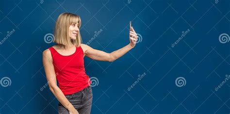 Slim Blonde Womanin Red T Shirt On A Blue Studio Background Making