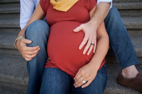 a pregnant woman sitting on the steps with her husband