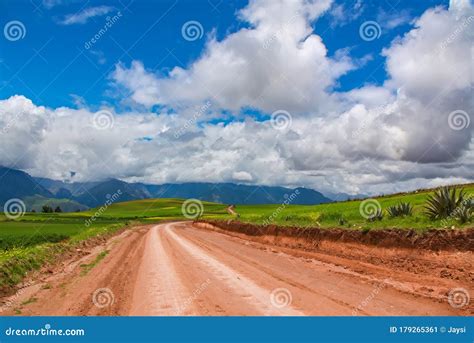 Beautiful Landscape Of Gravel Road Fields Meadows And Mountains In
