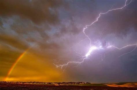 Stunning A Bolt Of Lightning Streaks Toward A Rainbow As A