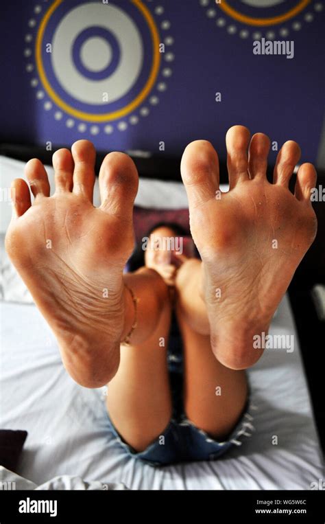 Young Woman Showing Sole Of Feet While Lying On Bed At Home Stock Photo