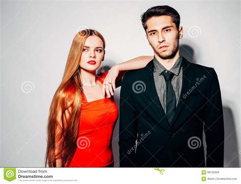 Young Fashion Man And Woman Against White Wall Posing For The Camera