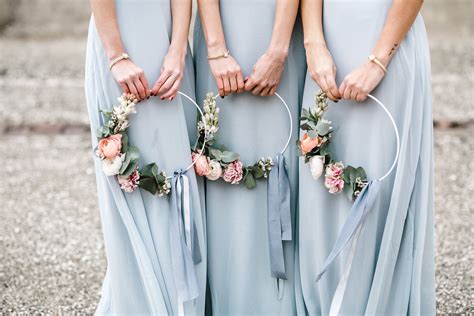three bridesmaids in blue dresses holding flower hoop wreaths