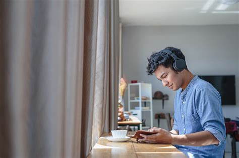 Young Asian Handsome Man Listening To Music With Headphone And Reading