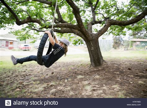 Boy Playing Swinging On Tire Swing Hanging From Tree Stock Photo Alamy