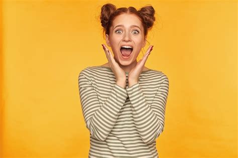 Free Photo Pretty Ginger Woman With Two Buns Touching Her Cheek And Looking Shocked Wearing