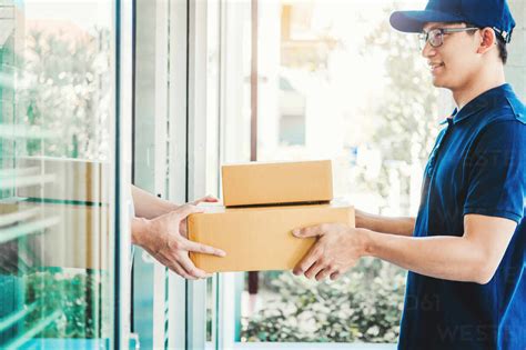 Smiling Delivery Man Giving Package To Customer Stock Photo