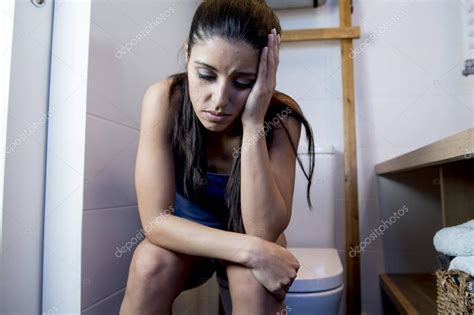 Young Sad And Depressed Bulimic Woman Feeling Sick Sitting In Toilet Wc Looking Desperate And