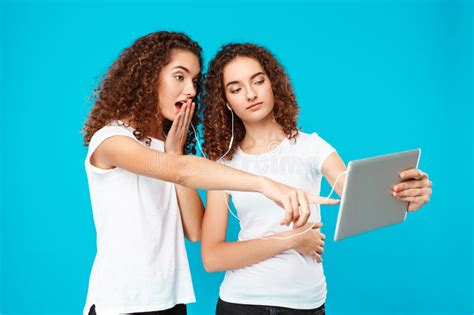 Two Surprised Girls Twins Pointing Finger Away Over Blue Background Stock Image Image Of