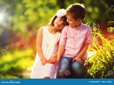 Niños Lindos En El Amor Sentándose Junto En Jardín De La Primavera