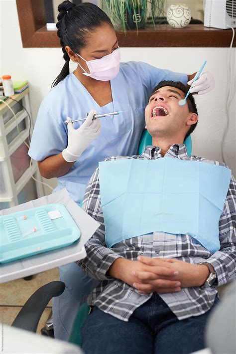 Dentist Preparing A Treatment On A Patient By Stocksy Contributor