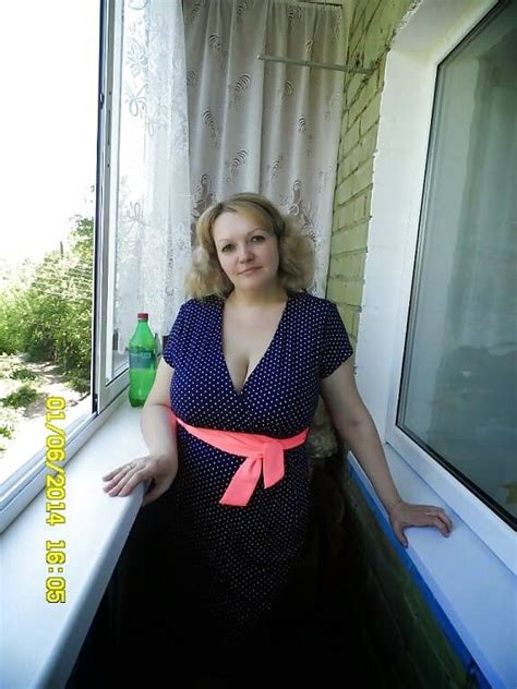 A Woman Standing In Front Of A Window Next To A Green Bottle
