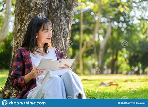 Happy Asian Female Reading A Book Daydreaming About Her Success While