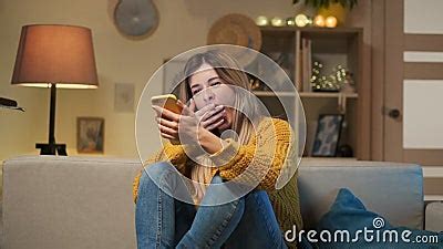 Tired Girl Sitting On The Sofa With Cell Phone Texting Message Bored Woman Yawning Near