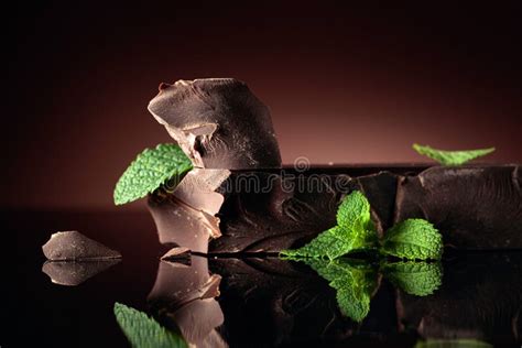 Large Piece Of Dark Chocolate With Mint On A Black Reflective
