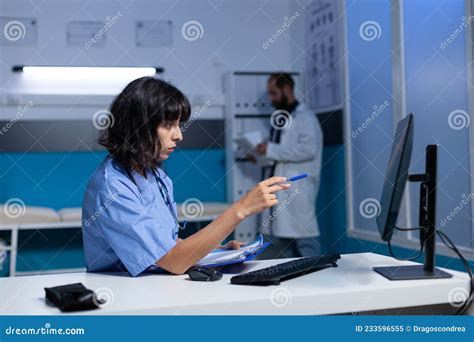 Nurse Doing Overtime Work With Computer And Checkup Files Stock Image