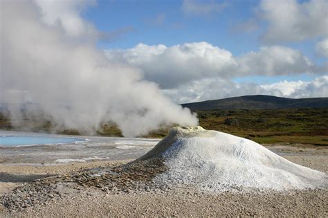 Steam Rises From The Ground In Front Of A Geyser