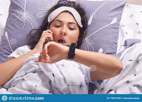 Astonished Woman Wearing Pajama And Sleeping Mask Posing With Opened Mouth Looking At Smart