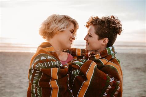 loving lesbian couple wrapped in a blanket at the beach stock image