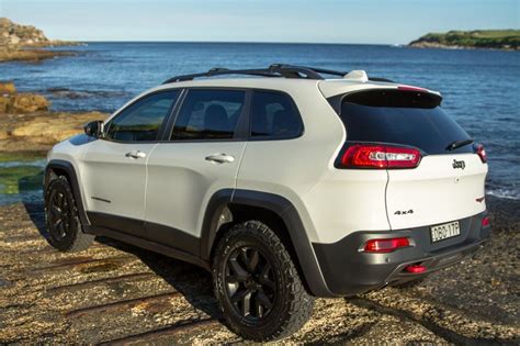 A White Jeep Parked On Top Of A Rocky Beach