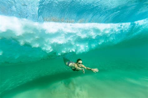 Ocean Swim A Wave Breaks Toward Shore As A Swimmer Dives Under It