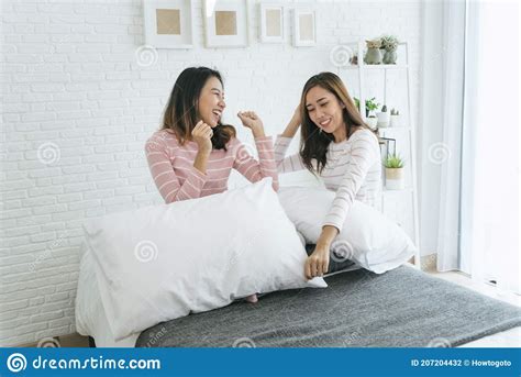 two pretty best friends forever girlfriend talk hug and laugh together on bed at cozy home