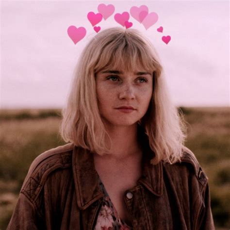 A Woman With Blonde Hair Wearing A Brown Jacket And Pink Hearts Above Her Head In The Desert