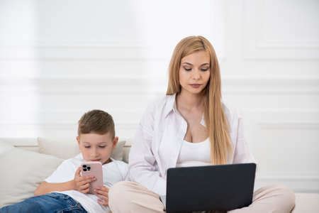 Mom And Son On The Couch Sitting On The Phone Serious Face Of Mother