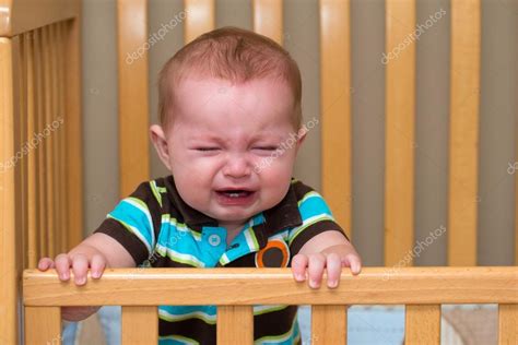 Crying Unhappy Baby Standing In His Crib Stock Photo By ©robhainer 49892025