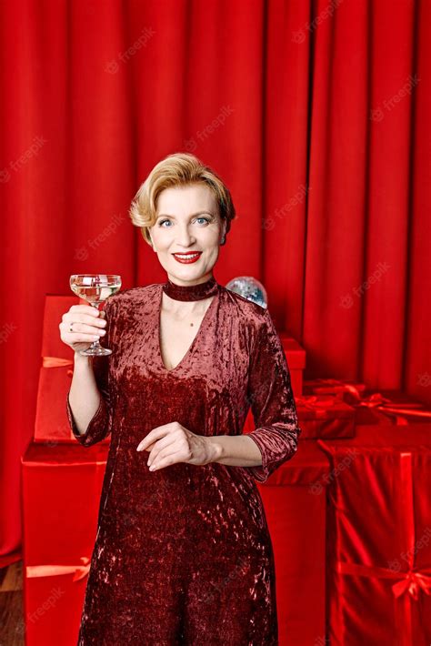 Premium Photo Mature Stylish Elegant Woman With Glass Of Sparkling Wine With Presents On Red