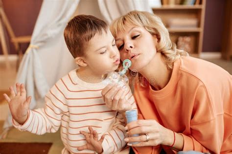 Portrait Of Mother And Son With Down Syndrome Blowing Bubbles Together