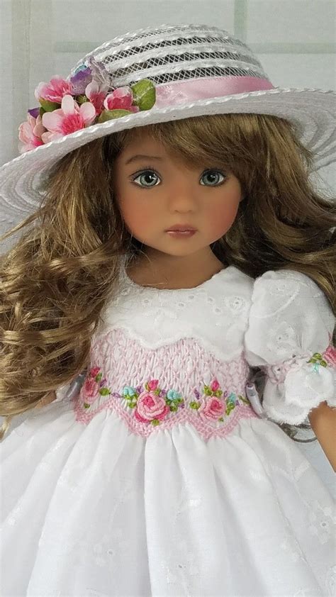 A Doll Wearing A White Dress And Hat With Pink Flowers On Its Head