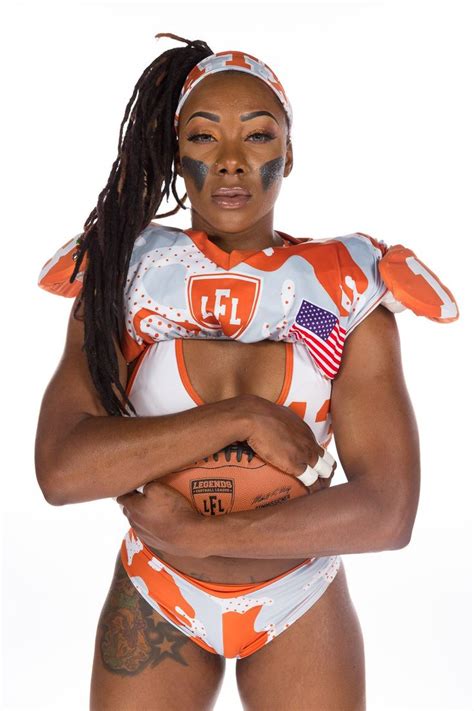 a woman in an orange and white football uniform holding a ball with her arms crossed